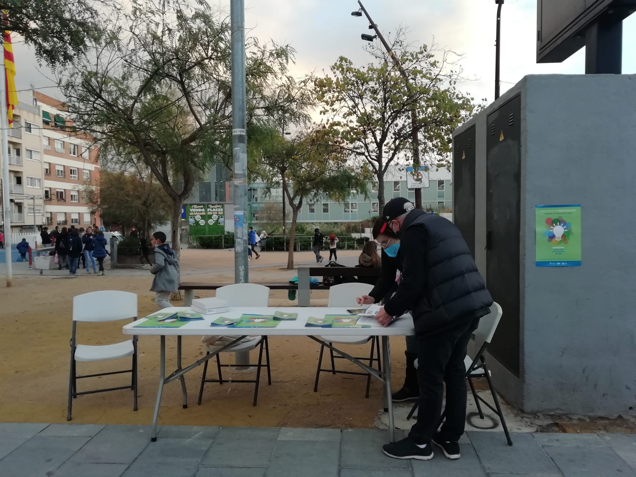 Pressupostos participatius: Dos persones al carrer al voltant d'una taula amb folletons