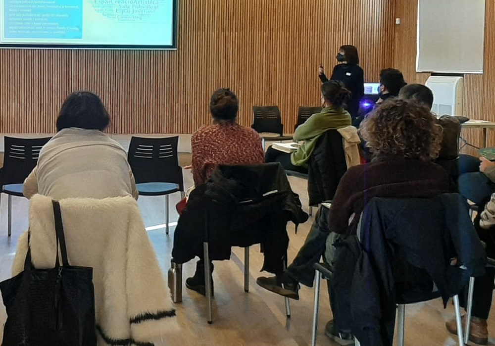 Sala de conferències amb l'audiència d'esquenes i imatge projectada al davant